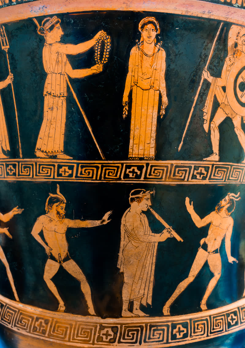 Pandora, recém-criada, está de frente como uma estátua, e Atena se aproxima para lhe pôr a coroa; à direita, Ares armado. Embaixo, um flautista e um coro de Pãs dançando. Lado A de uma cratera de cálice ática de figuras vermelhas, ca. 460–450 a.C., do Pintor dos Nióbidas; achada em Altamura. British Museum, Londres (1856,1213.1 · E 467).